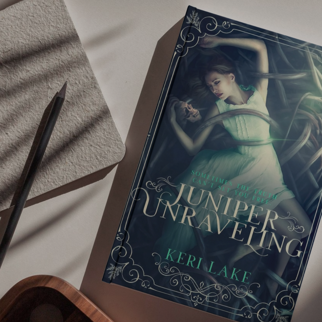 Book titled 'Juniper Unraveling' by Keri Lake on a surface with a pen and notebook.