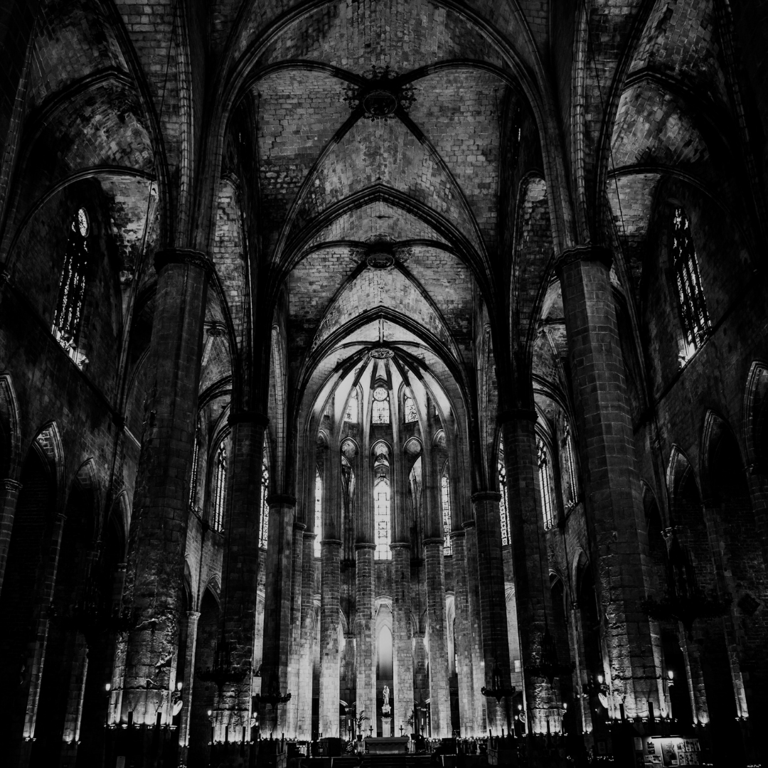Dark cathedral interior with high vaulted ceilings and stained glass windows.